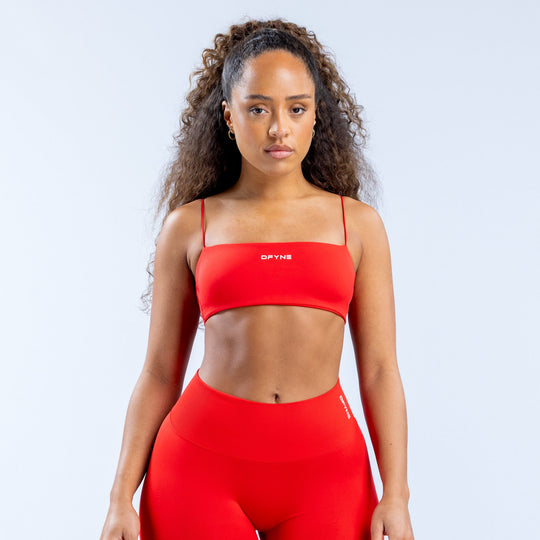 Red strappy sports bra with supportive band, smooth cups, and center logo