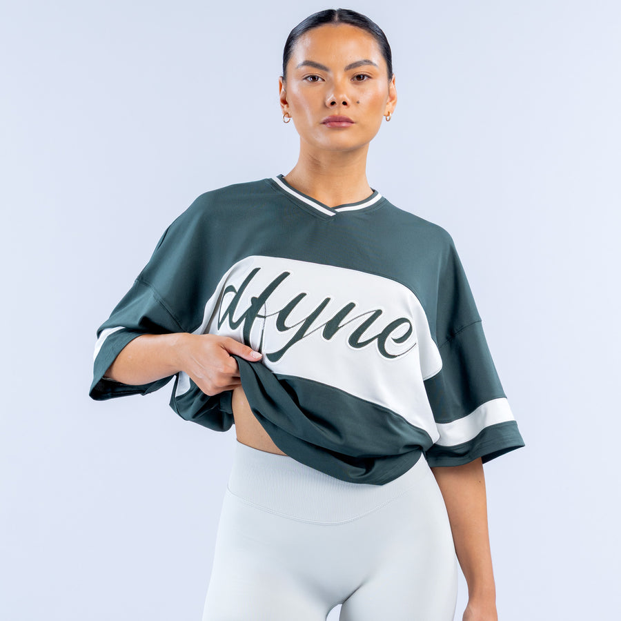 Dark green short sleeve top with white V-neck trim and 'Mtyme' logo