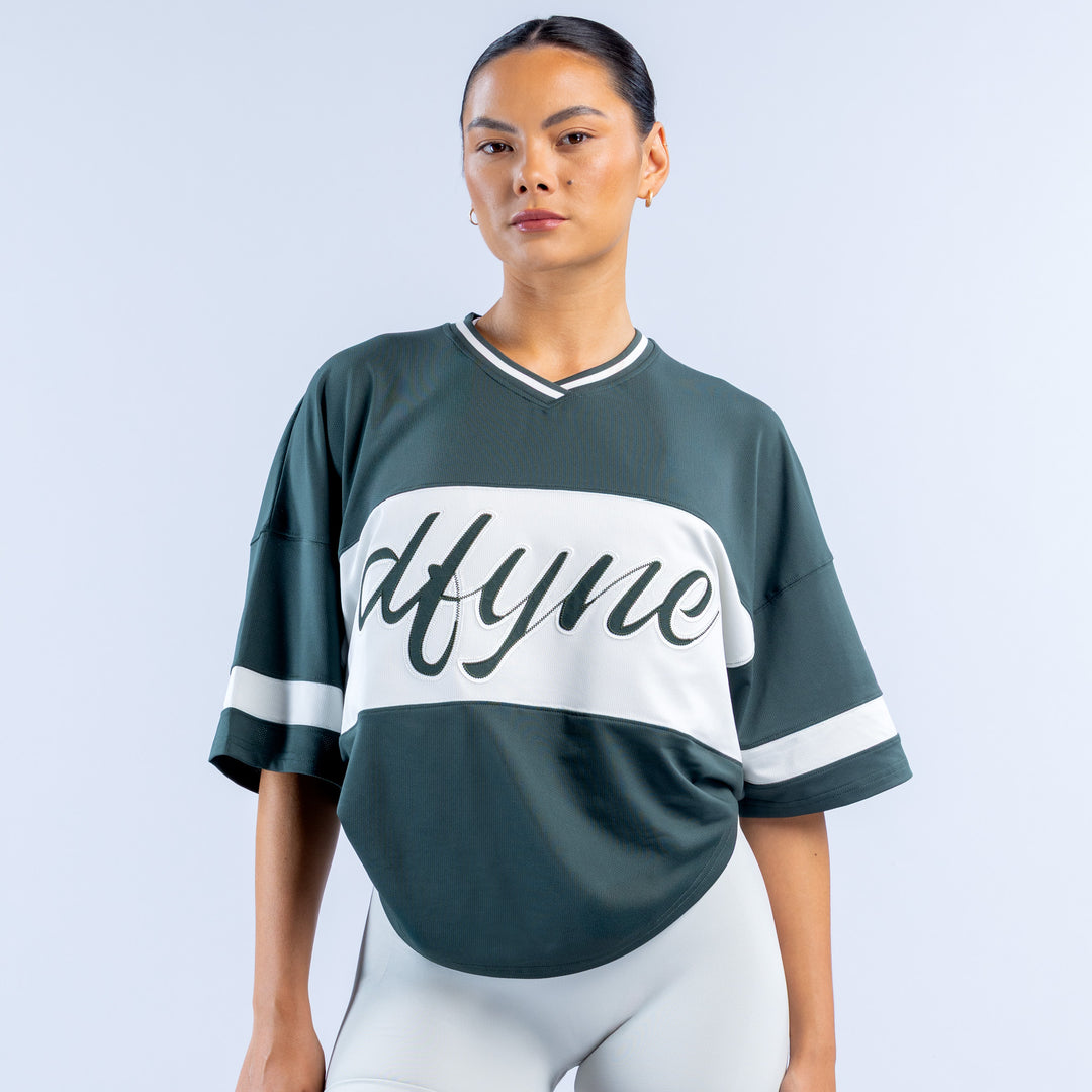 Dark green short sleeve top with white V-neck trim and large 'Mtyme' graphic