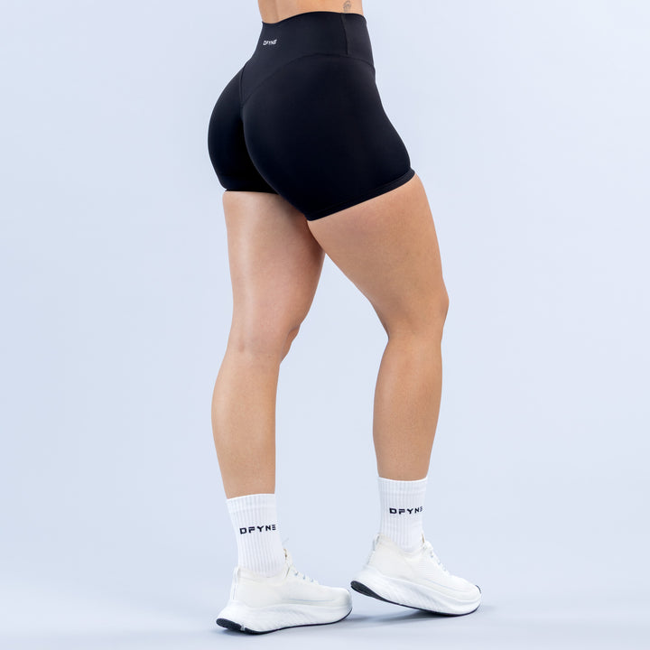 Women's black 4.5" biker shorts, back view, sculpting seams and elastic waistband