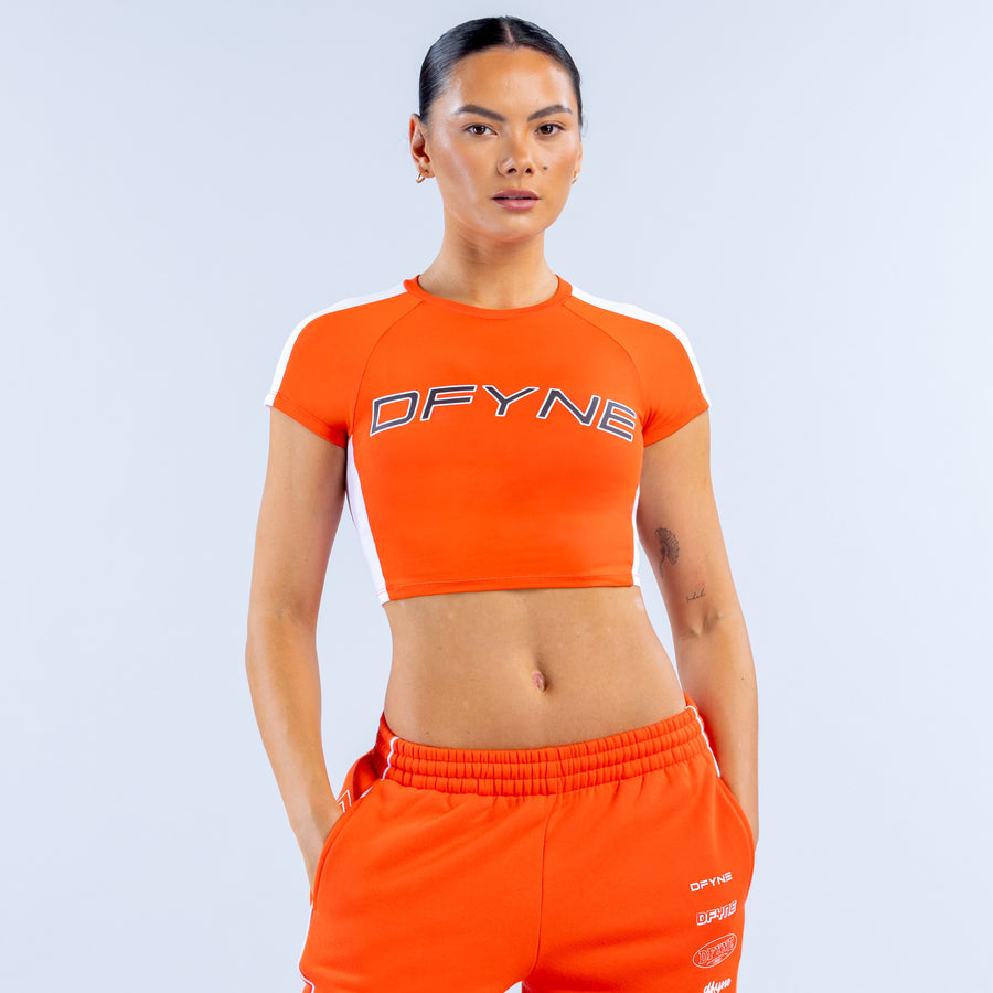 Orange baby graphic tee with white shoulder panels and DFYNE chest logo