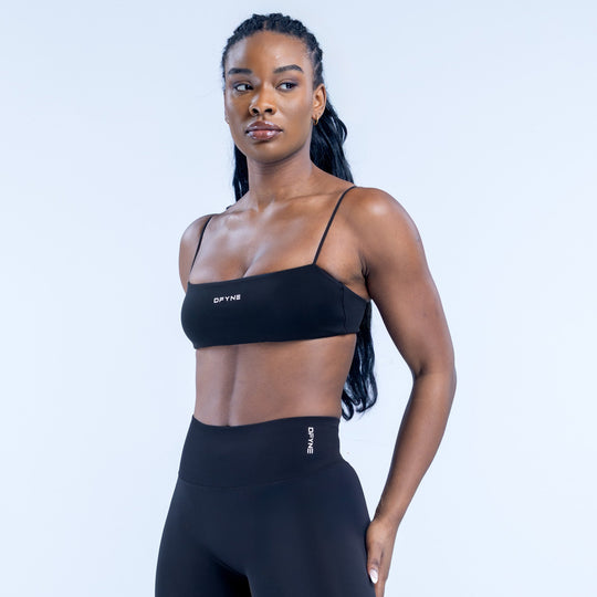 Black strappy sports bra with thin straps and DYNE logo at center
