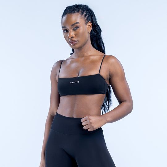 Black strappy sports bra with adjustable thin straps and DYNE logo band