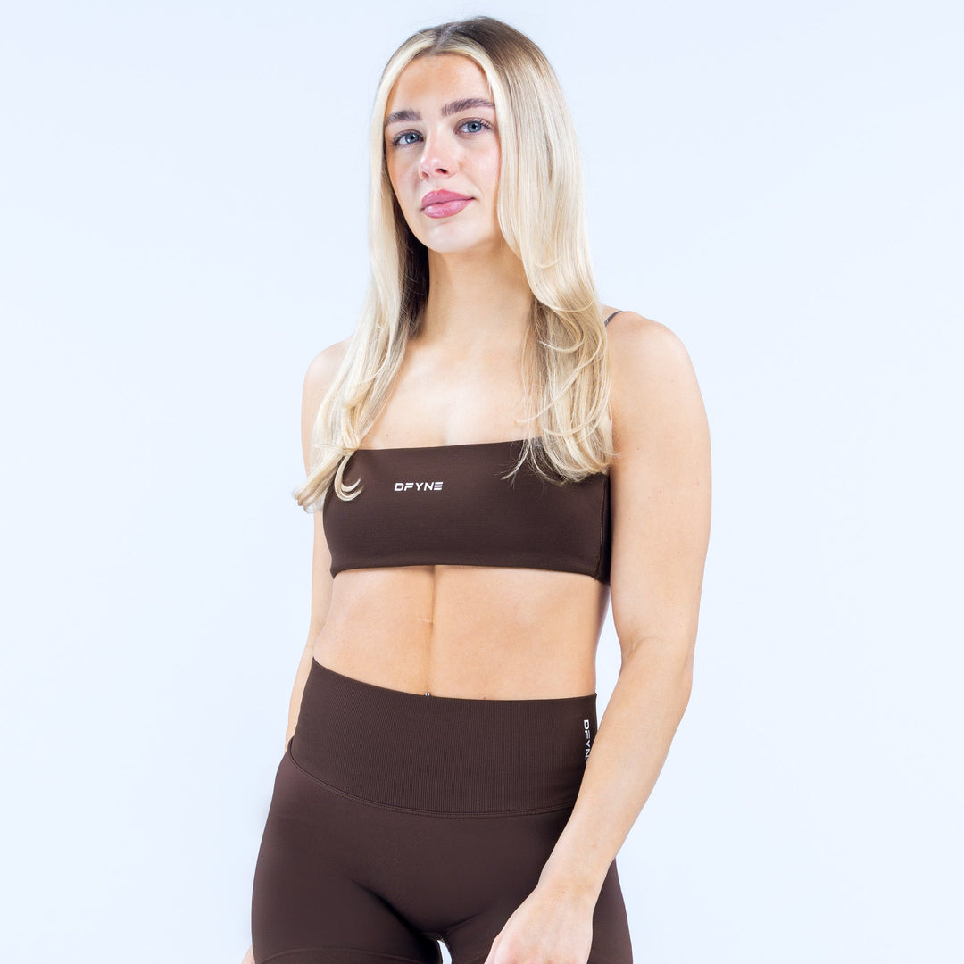 Women’s strappy sports bra in dark fabric with elastic band and small center logo