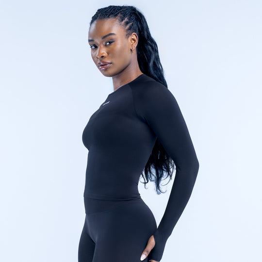 Fitted black long sleeve top side view with crew neck and chest logo