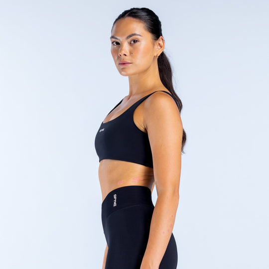 Black scoop-back sports bra with racerback straps and curved underbust seams.