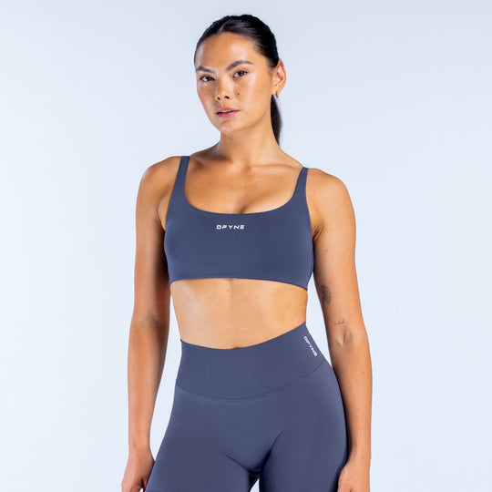 Scoop-back sports bra in dark navy, racerback straps and minimal logo front