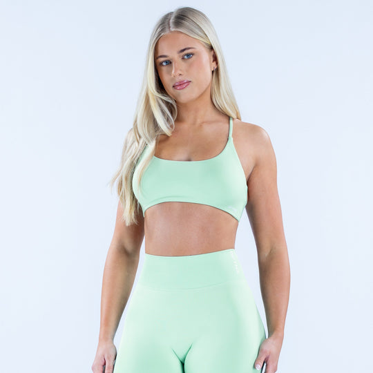 Mint green twist-back sports bra with thin straps and front scoop neckline