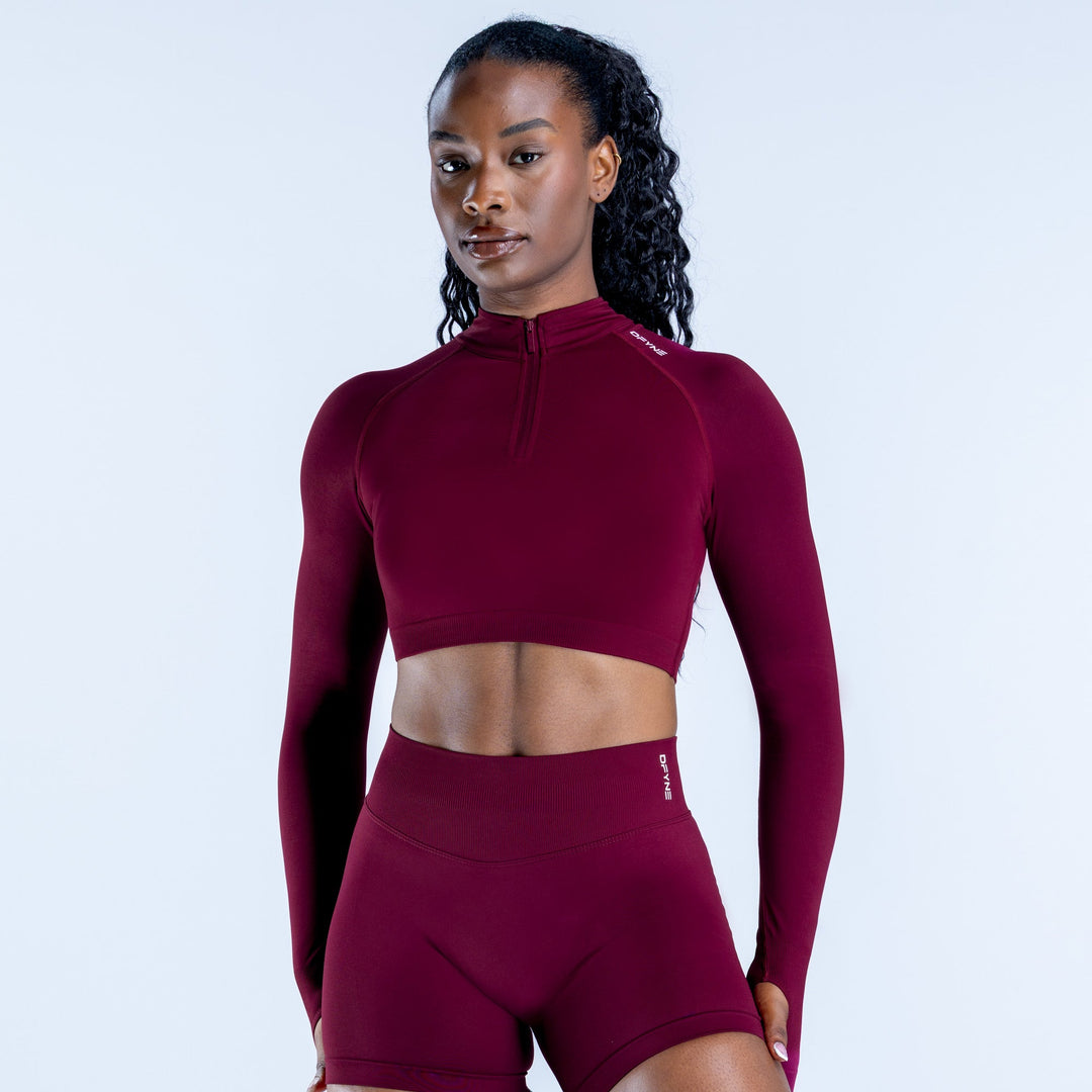 Burgundy long-sleeve zip-front crop top, high neckline, fitted athletic fabric