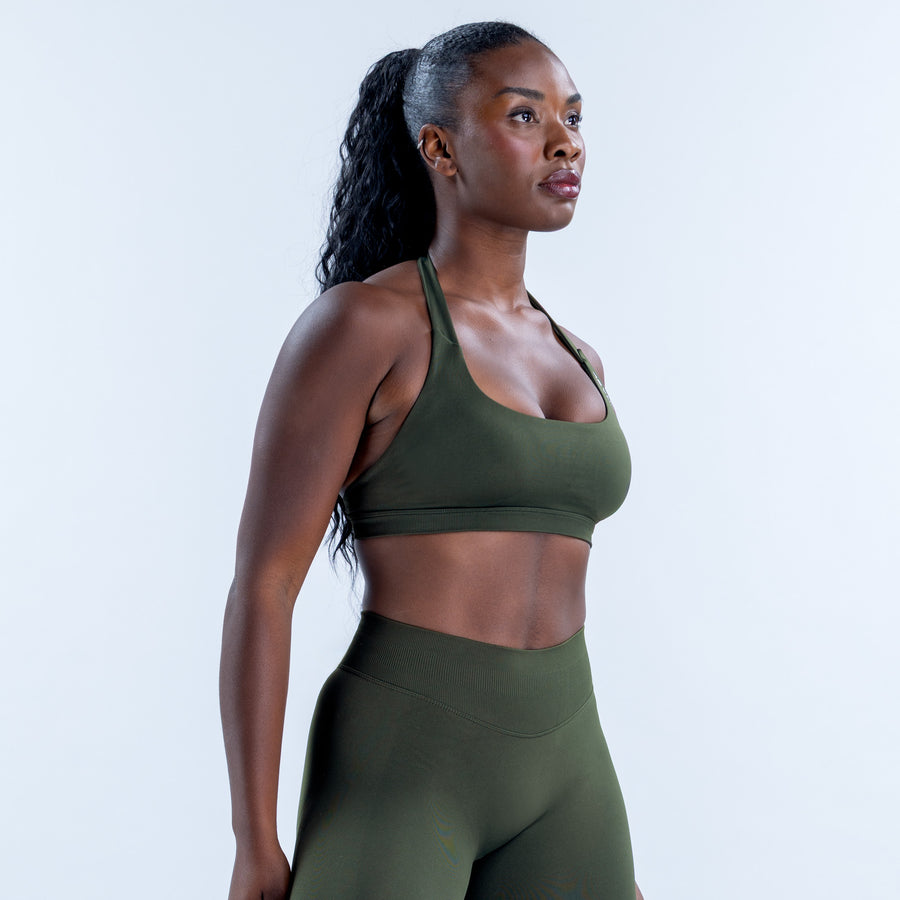 Side view of a dark olive sports bra with halter straps and a wide underband.