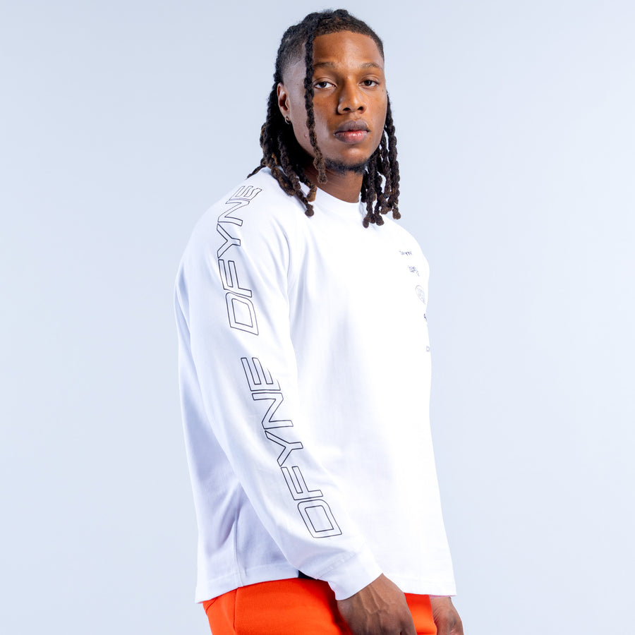 White long-sleeve kids top with vertical logo print on sleeve; orange shorts visible