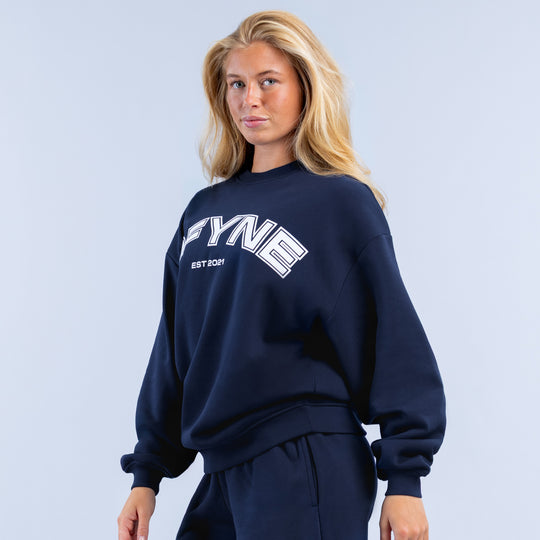 Navy crewneck sweatshirt with small DFYNE logo graphic on chest, ribbed hem