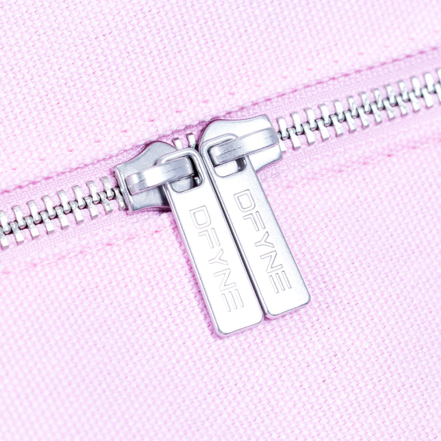 Silver zipper pull with logo tag on light pink duffle bag.