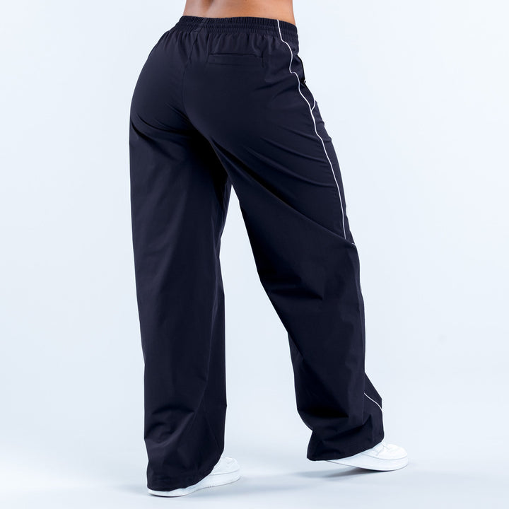 Dark track pants with elastic waistband and white piping stripe at side seams
