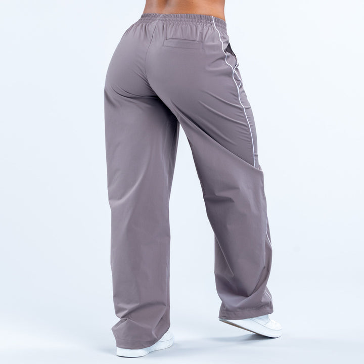 Dark gray track pants with white side piping, elastic waist and relaxed fit