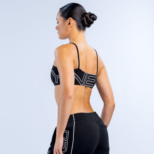 Girls' black sports bra with thin back straps and large white logo on back