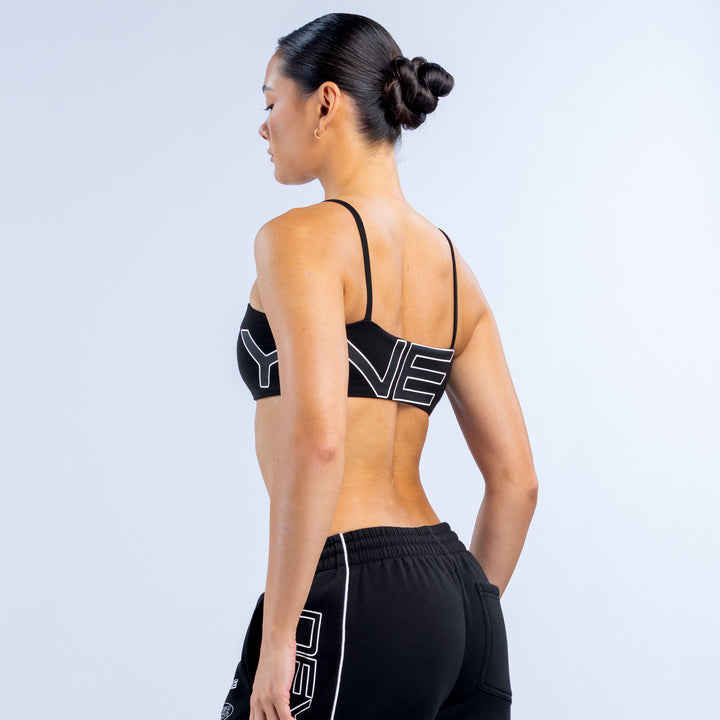 Girls' black sports bra with thin back straps and large white logo on back