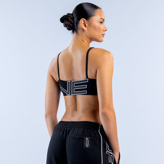 Girls' black sports bra with racerback style and white logo graphic on back