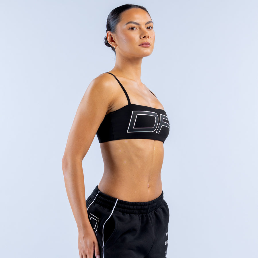 Girls' black sports bra with thin straps and white logo graphic across chest