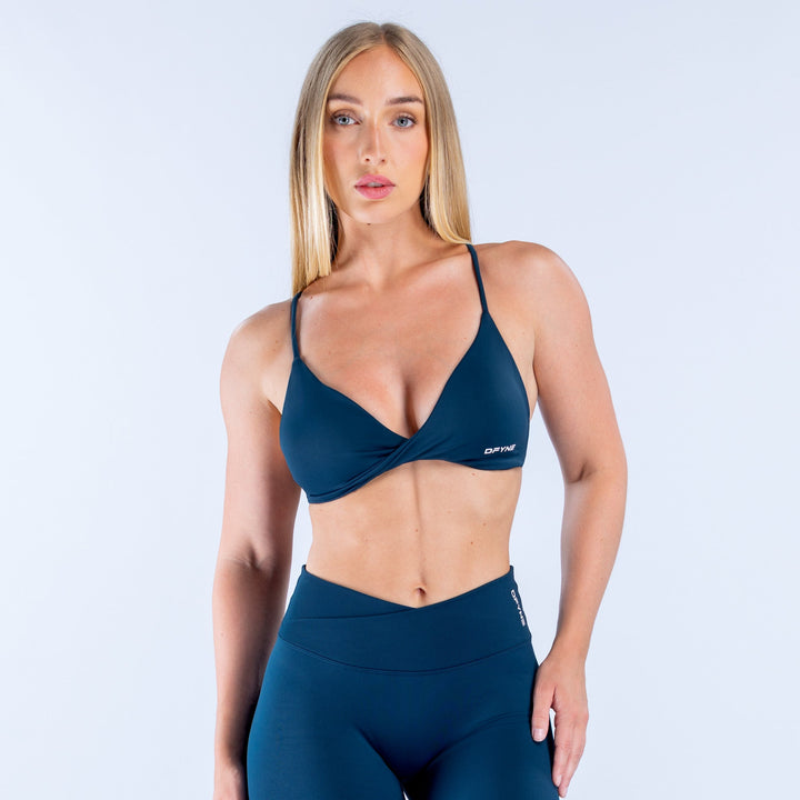 Dark teal twist-front sports bra with strappy neckline and DYFN logo band